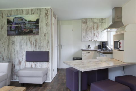 Interno lodge moderno con cucina, tavolo da pranzo e sedute a Veluwecamping De Pampel, Paesi Bassi.