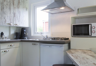 Moderne tekøkken i Forest Lodge på Veluwecamping De Pampel, Holland, med mikrobølgeovn og gaskomfur.