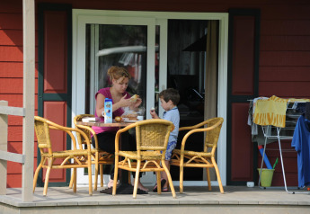 Una donna e un bambino condividono un pasto sul portico della Forest Lodge a Veluwecamping De Pampel, Paesi Bassi.