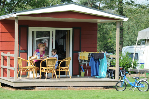 Een moeder en zoon ontbijten samen op het terras van een Forest Lodge bij Veluwecamping De Pampel, Nederland.