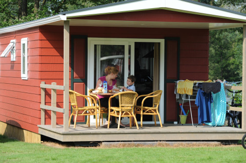 Famiglia fa colazione sulla veranda del Forest Lodge a Veluwecamping De Pampel nei Paesi Bassi.
