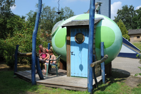 Family sitting outside the Dreaming in a Dragon's Egg pod at Veluwecamping 't Schinkel, Netherlands.