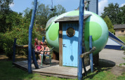 Family sitting outside the Dreaming in a Dragon's Egg pod at Veluwecamping 't Schinkel, Netherlands.