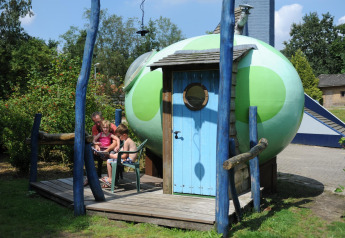 Gezin zit buiten bij Dreaming in a Dragon's Egg pod op Veluwecamping 't Schinkel in Nederland.