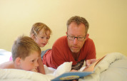 Un homme lit un livre à deux enfants sur un lit dans le pod Dreaming in a Dragon's Egg aux Pays-Bas.