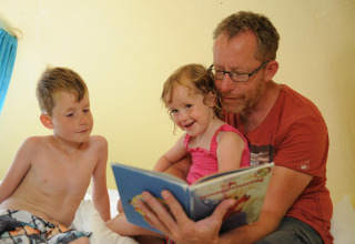 Un padre lee un libro a su hijo e hija en el pod Dreaming in a Dragon's Egg, en Veluwecamping 't Schinkel, Holanda.