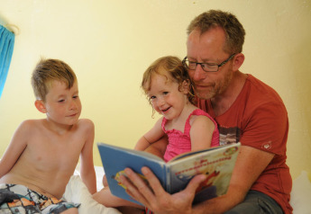 Un padre lee un libro a su hijo e hija en el pod Dreaming in a Dragon's Egg, en Veluwecamping 't Schinkel, Holanda.