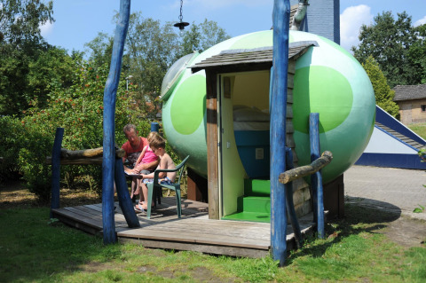En familie sidder udenfor en pod kaldet Dreaming in a Dragon's Egg på Veluwecamping 't Schinkel i Holland.