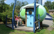 Famiglia rilassata accanto al pod Dreaming in a Dragon's Egg al Veluwecamping 't Schinkel, Paesi Bassi.