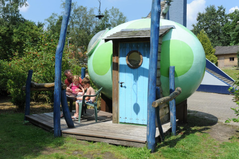 Gezin geniet buiten bij de Dreaming in a Dragon's Egg pod op Veluwecamping 't Schinkel in Nederland.