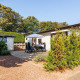Ferienhaus im EuroParcs Noordwijkse Duinen, Niederlande, mit Menschen, die draußen auf der Terrasse sitzen.