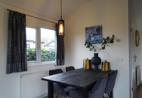 Modernes Esszimmer in einer Hütte im EuroParcs Noordwijkse Duinen, Niederlande, mit dunklem Tisch.