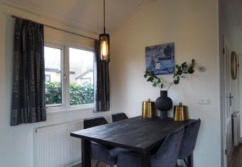 Et moderne spiseområde i en hytte på EuroParcs Noordwijkse Duinen med sorte stole og udsmykning.