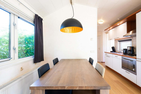 Lichte keuken en eetkamer met houten tafel in een vakantiehuis bij EuroParcs Noordwijkse Duinen, Nederland.