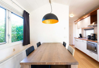 Lichte keuken en eetkamer met houten tafel in een vakantiehuis bij EuroParcs Noordwijkse Duinen, Nederland.