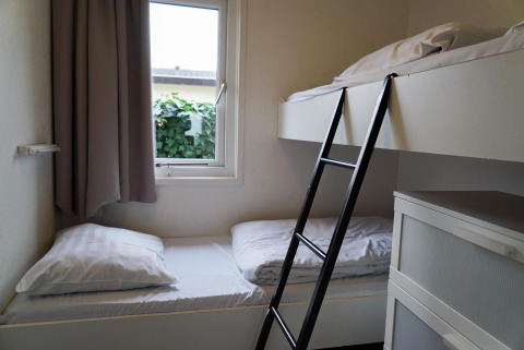 Zimmer mit Etagenbett, Leiter und Fenster in einem Ferienhaus bei EuroParcs Noordwijkse Duinen, Niederlande.