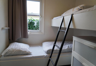 Chambre avec lits superposés, échelle et fenêtre dans une maison de vacances à EuroParcs Noordwijkse Duinen, Pays-Bas.