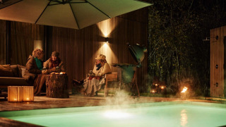 Drie mensen genieten van een avond bij het zwembad en de sauna bij Unbrick One Lodge, warm aangekleed.