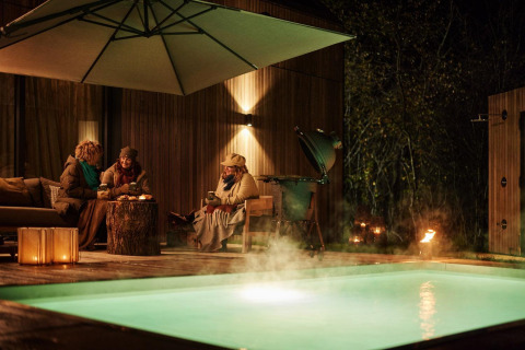 Trois personnes partagent une soirée près de la piscine chauffée à Unbrick One Lodge, ambiance chaleureuse.