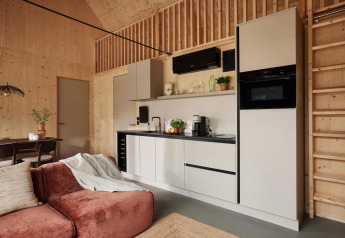 Moderne Küche in einer Lodge mit Holzvertäfelung, gemütlichem Sofa und Essbereich im offenen Raum.