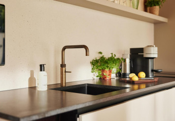 Cuisine moderne de lodge avec robinet en laiton, cafetière, herbes en pot et citrons sur le plan de travail.