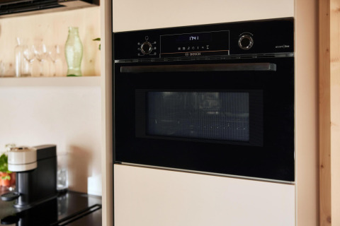 Eingebauter Bosch-Backofen in einer modernen Lodgeküche, Glaswaren und Kaffeemaschine im Hintergrund.