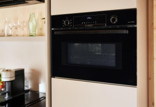 Forno Bosch incassato in una cucina moderna di una lodge, vetri e macchina da caffè visibili sul piano.