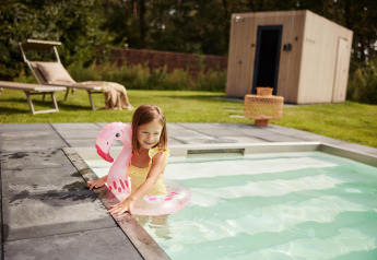 Bambina in costume giallo con gonfiabile fenicottero rosa nella piscina di Unbrick One, De Weelderik, Paesi Bassi.
