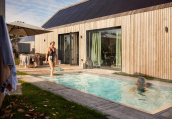 Esterni di Unbrick One Lodge: persone rilassate in piscina con sauna e terrazza in legno moderna.