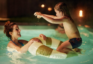 Una madre y su hija juegan alegres en la piscina iluminada de Unbrick One Family | Sauna and Pool en De Weelderik, Países Bajos.