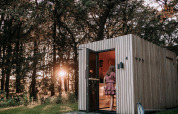 Modernes Saunahaus aus Holz am Waldrand mit Sonnenuntergang im Hintergrund bei De Weelderik, Niederlande.