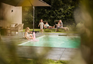 Gezin ontspant bij het zwembad bij Unbrick One Family | Sauna en Pool te De Weelderik in Nederland.