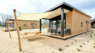 Sand Lodge Sauna, pequeña casa en Holiday Park De IJsvogel, Países Bajos, terraza y sombra en la arena.