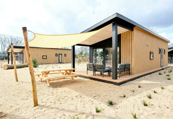 Sand Lodge Sauna, pequeña casa en Holiday Park De IJsvogel, Países Bajos, terraza y sombra en la arena.
