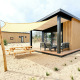 Sand Lodge Sauna, et lille hus på Holiday Park De IJsvogel i Holland, med terrasse og solsejl i sandet.