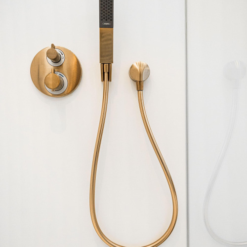 Moderna grifería de ducha de latón sobre pared blanca en Unbrick One | Sauna y Pool en De Weelderik, Países Bajos.