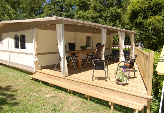 Safari glamping tent Cahors at La Draille in France, with spacious wooden deck, chairs, and relaxing vibe.