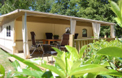 Überdachte Terrasse mit Stühlen und Tisch vor einem luxuriösen Safari-Zelt in La Draille, Cahors, Frankreich.