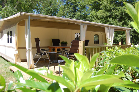 Udendørs terrasse med borde og stole foran en safari-glampingtelt på La Draille i Cahors, Frankrig.