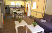 Indretning af en safari-glampingtelt ved La Draille med spisebord, sofabord, sofa og køkken i Frankrig.
