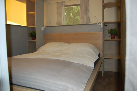 Slaapkamer in safaritent Glampingtent Cahors bij La Draille in Frankrijk met tweepersoonsbed en rekjes.