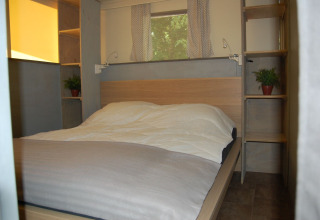 Slaapkamer in safaritent Glampingtent Cahors bij La Draille in Frankrijk met tweepersoonsbed en rekjes.