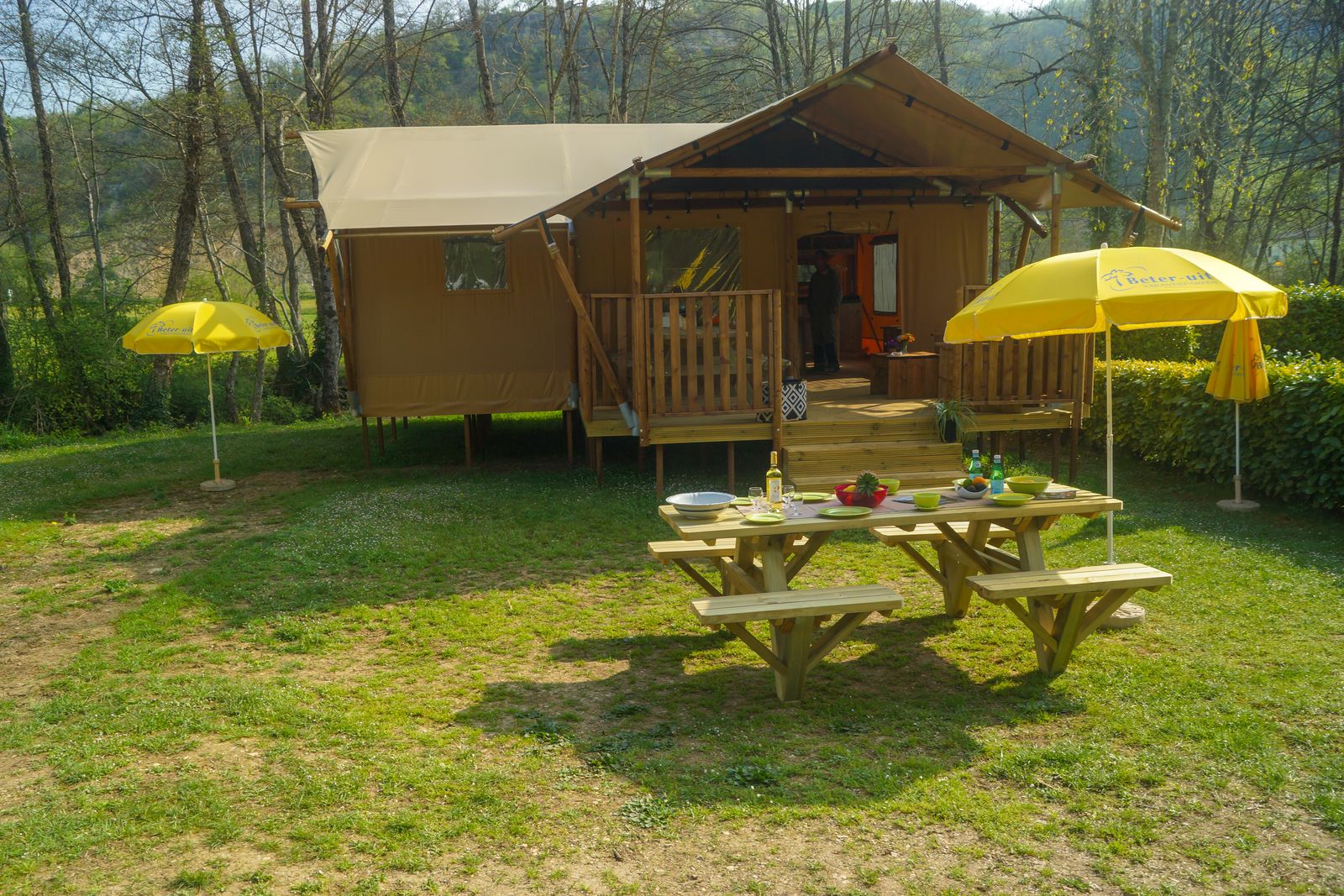 Safaritent Lodgetent Brive bij La Draille in Frankrijk, met picknicktafel en gele parasols buiten.