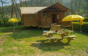 Safari-Zelt Lodgetent Brive bei La Draille in Frankreich mit Picknicktisch und gelben Sonnenschirmen.