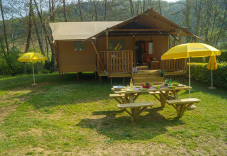 Safari tent Lodgetent Brive at La Draille in France, with a picnic table and yellow umbrellas outside.