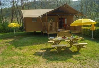 Safaritent Lodgetent Brive bij La Draille in Frankrijk, met picknickbank en gele parasols buiten.