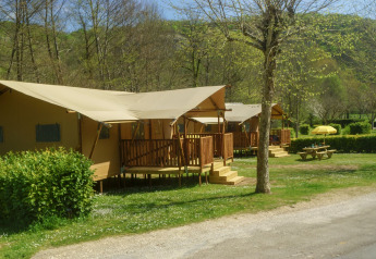 Safari tent Lodgetent Brive at La Draille in France, featuring a wooden deck and picnic table on grassy site.