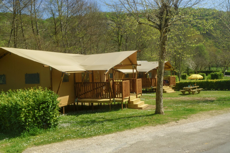 Tienda safari Lodgetent Brive en La Draille, Francia, con terraza de madera y mesa de picnic en el césped.