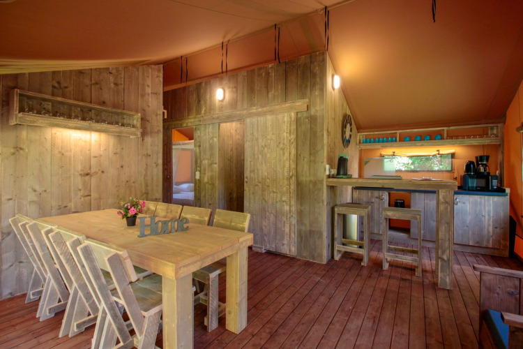 Interior del Lodgetent Brive en La Draille, Francia, con muebles rústicos de madera e iluminación cálida.