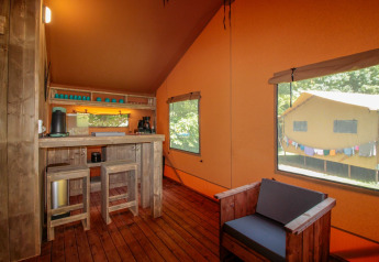 Interior de Lodgetent Brive en La Draille, Francia, con muebles de madera, cocina y grandes ventanas.